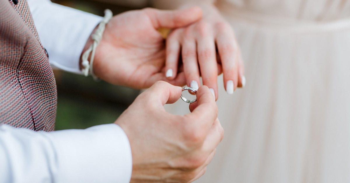 Man putting wedding ring on fiancée finger