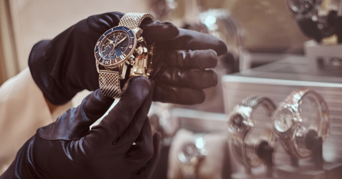 Close up of hands in gloves holding a designer watch